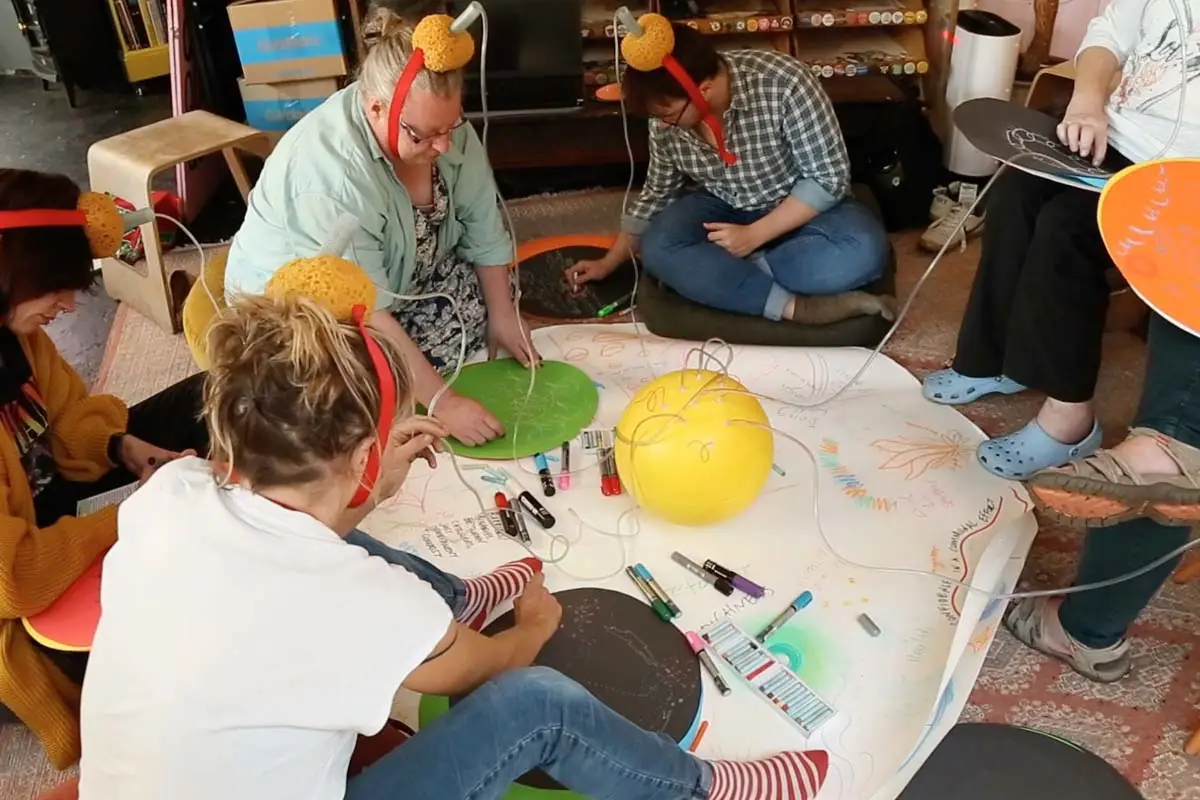 six people taking part in a drawing workshop in a queer bookshop, Scotland